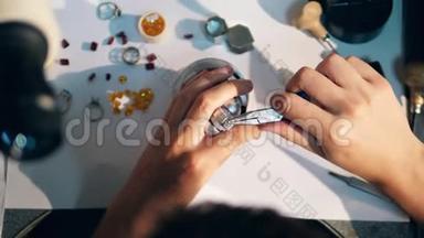 一个珠宝商用钳子拧紧戒指。 珠宝商，金匠在一个专业的珠宝车间。